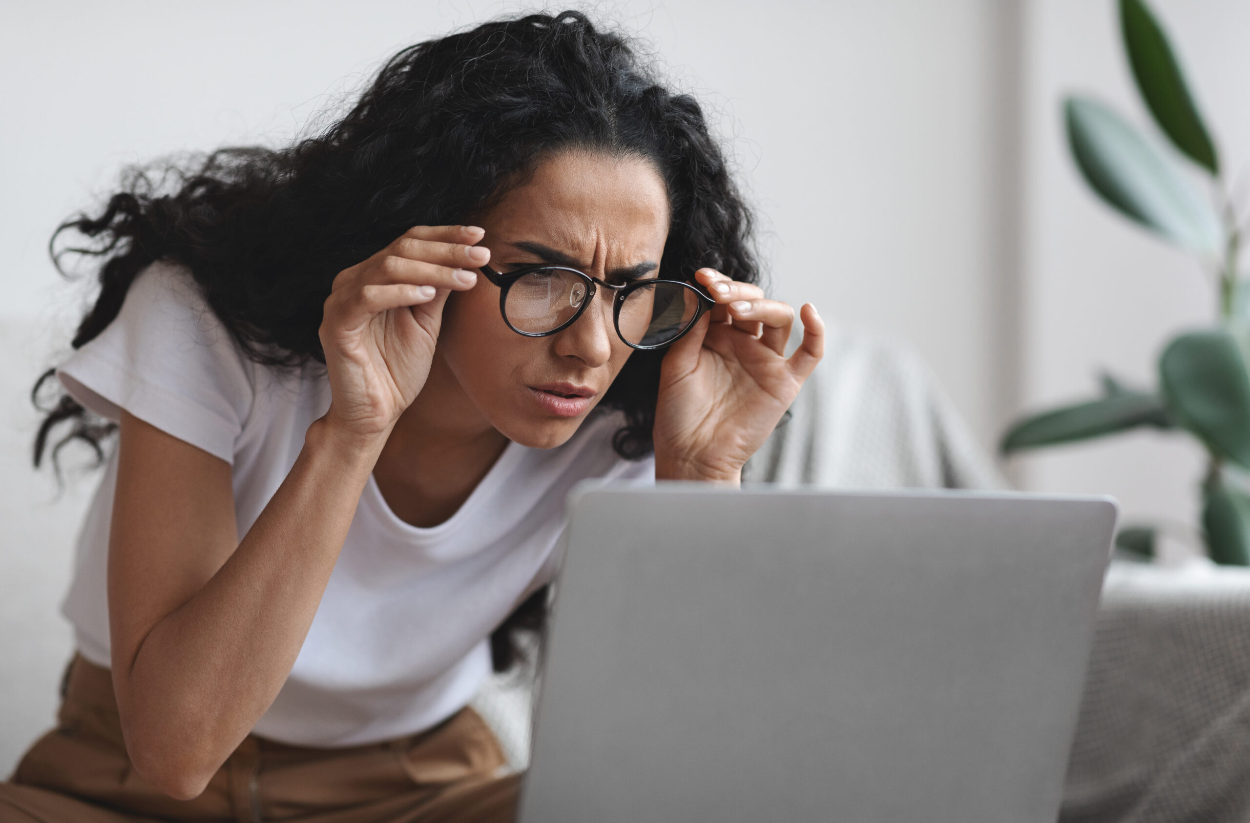 Young woman with bad eyesight using laptop, trying to work