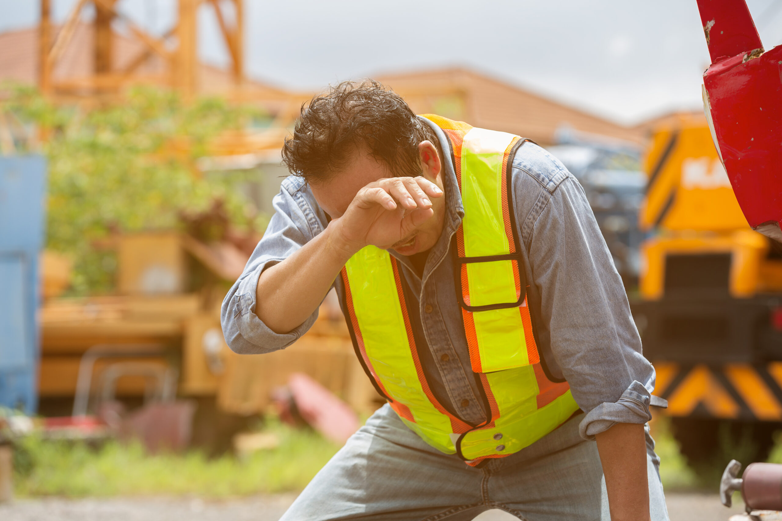 Senior Asian male construction builder tired and thirst of water at construction site. Construction workers have health problems and sick. Health safe of work and safety first concept