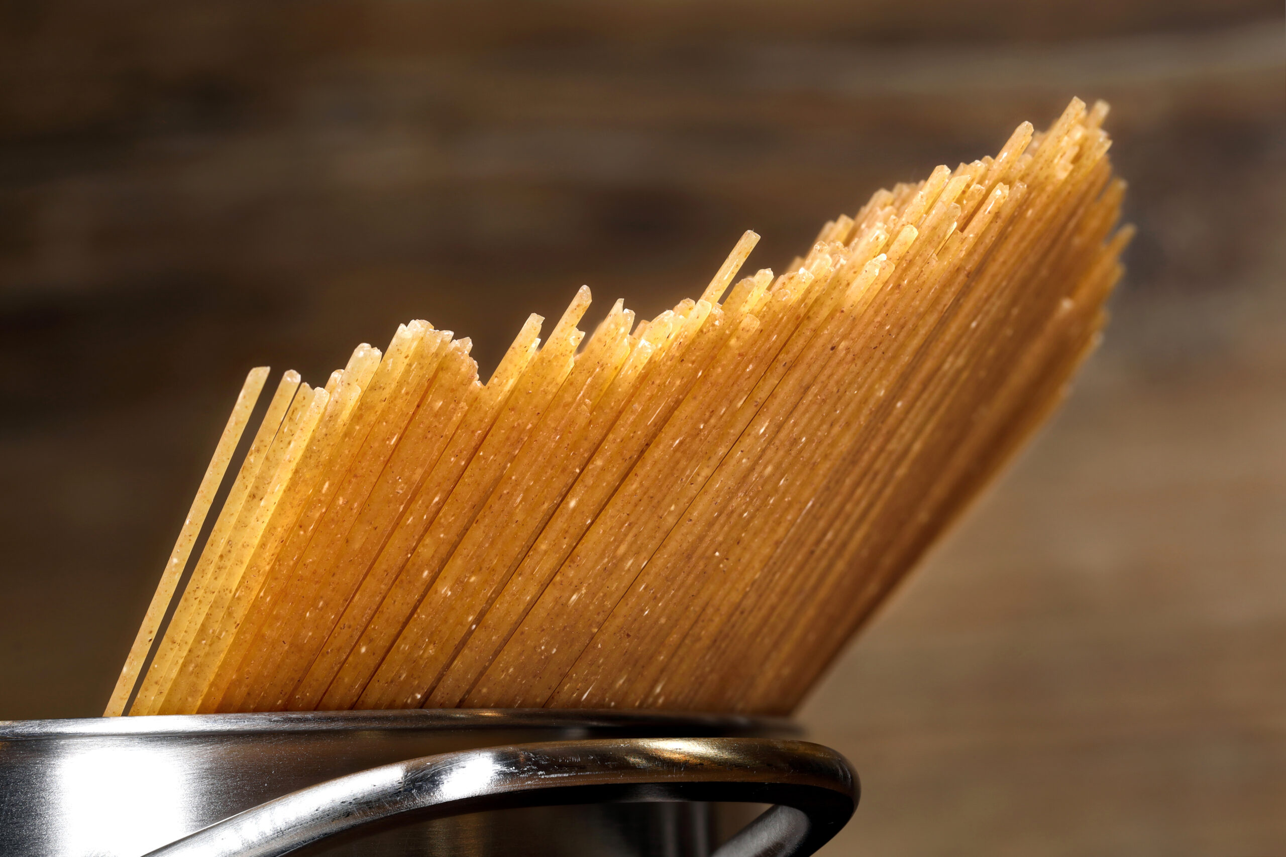 close up of uncooked whole grain spaghetti in pot, healthy, fiber-rich alternative to classic pasta