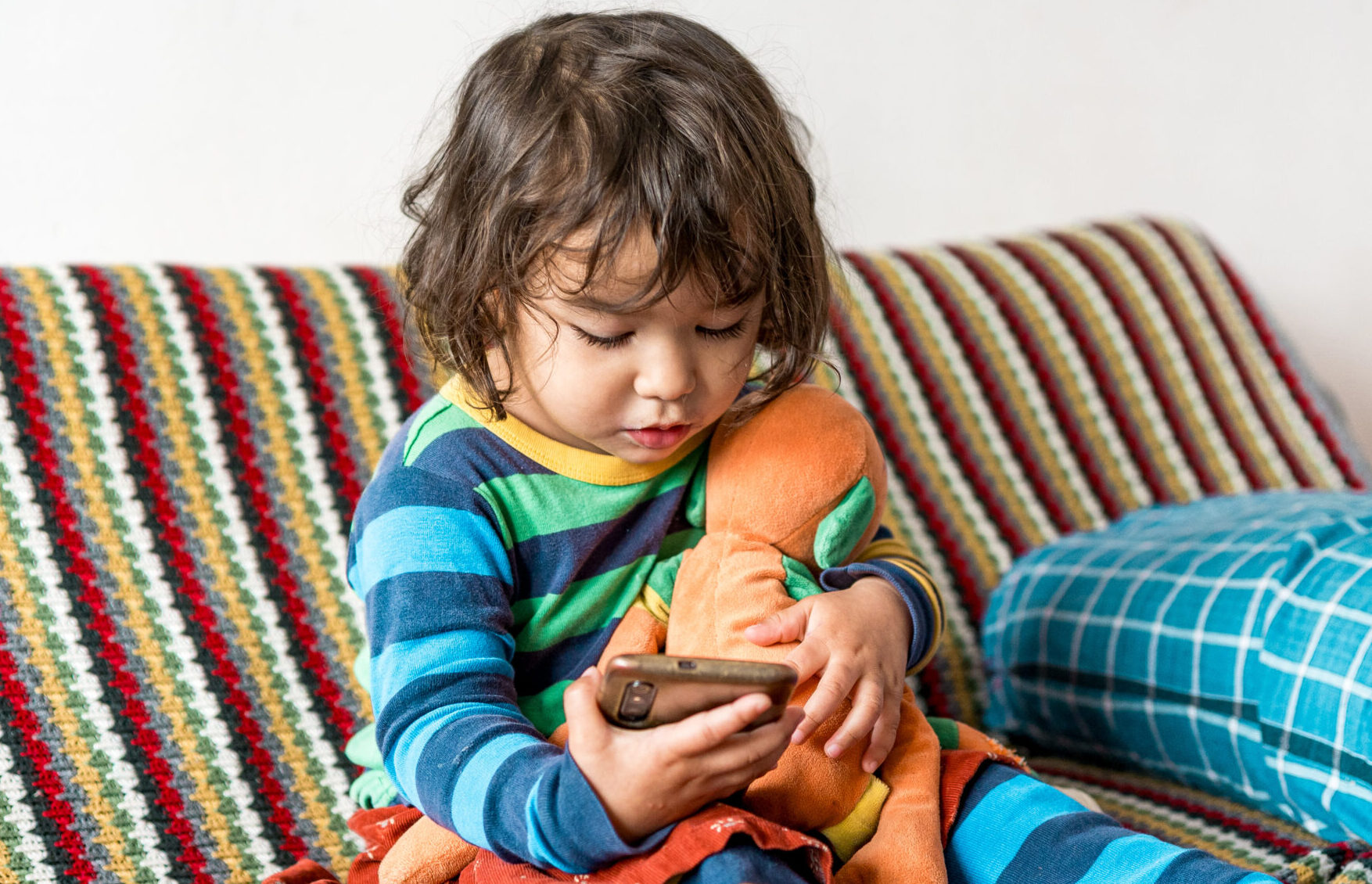 Baby girl child looking at cell phone screen checking children content in social networks. Concept of screen addiction and social media addiction in children