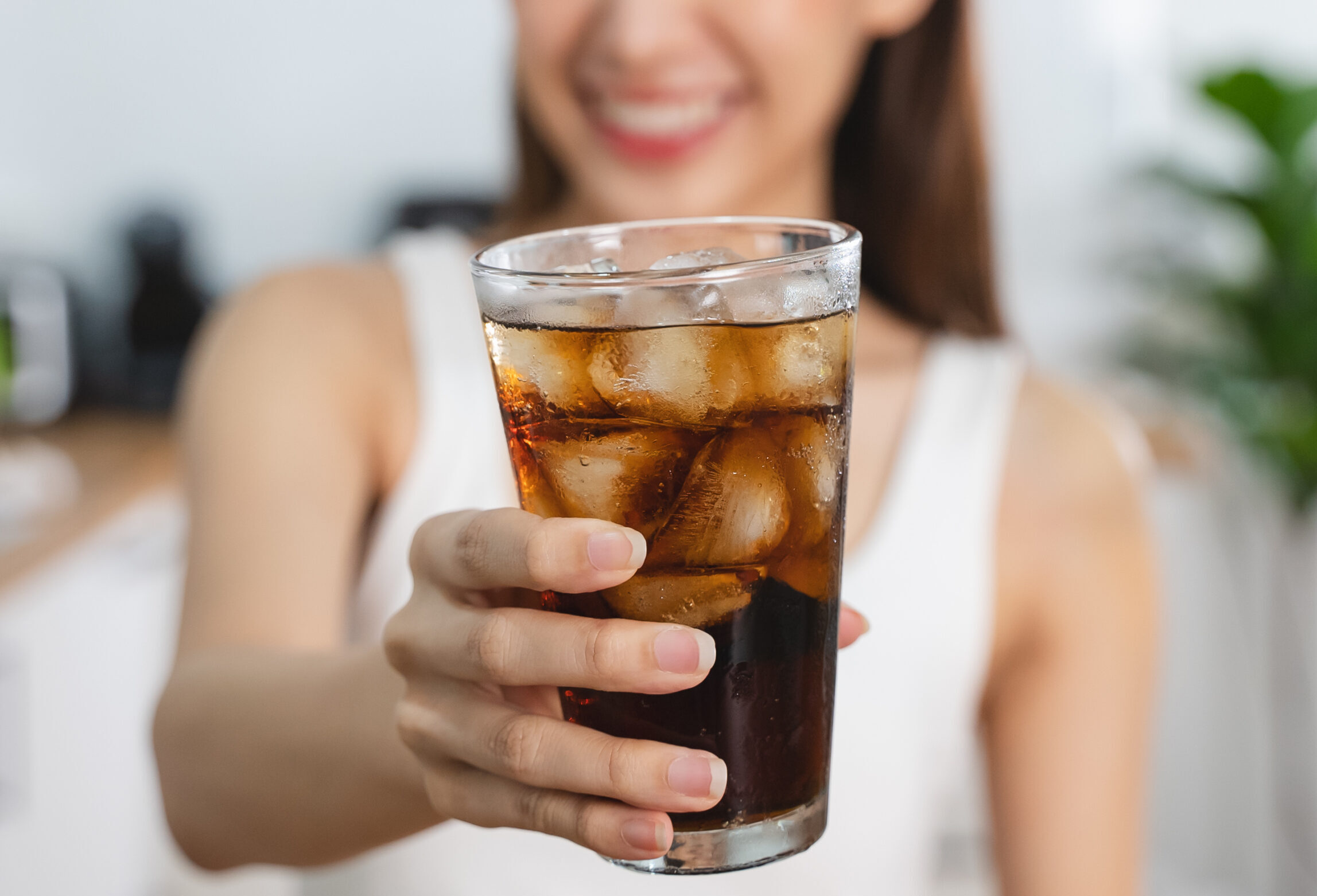 person smiling and holding a glass of soft drink soda