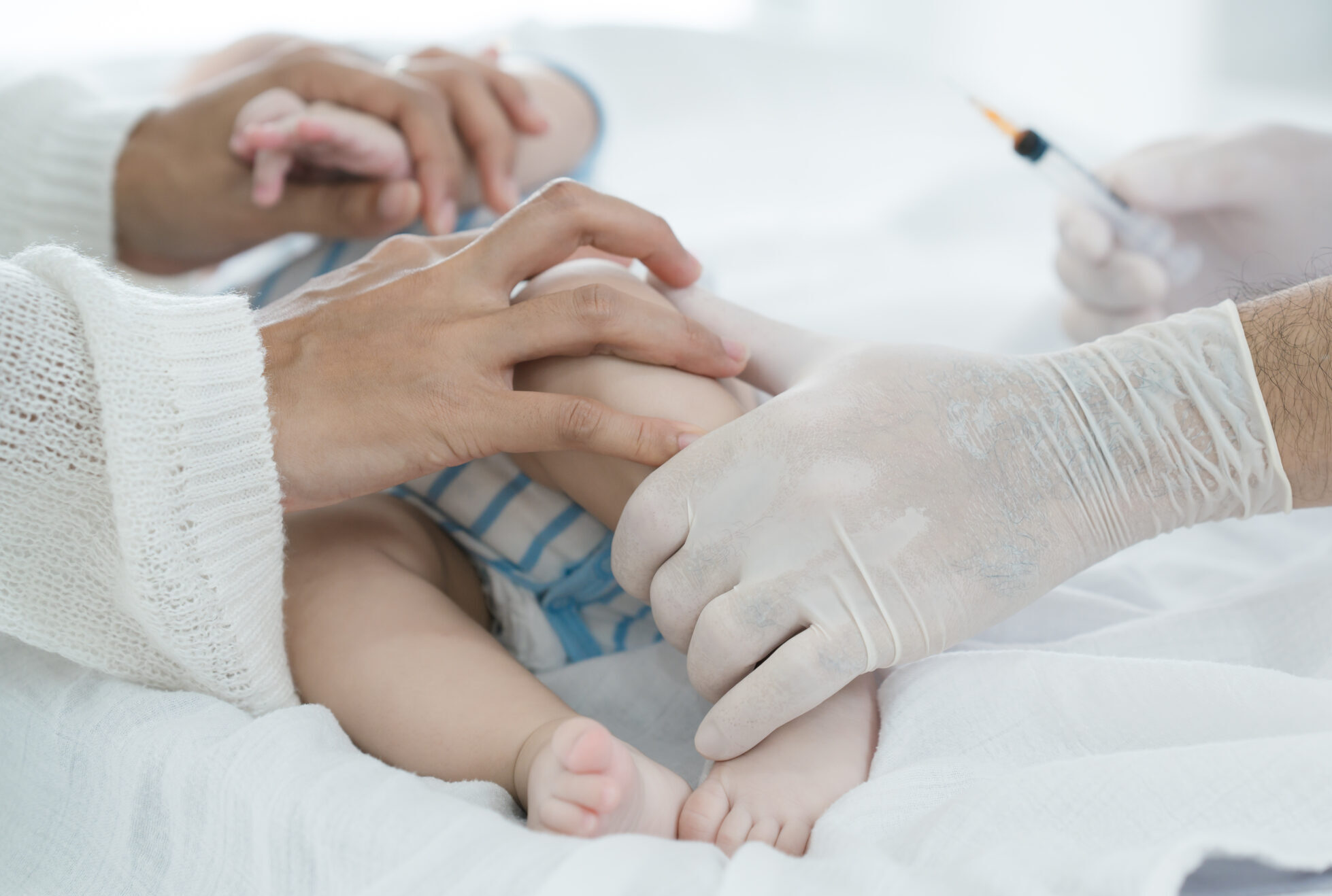 Asian loving mother comforts her three-month-old, as a male doctor administers essential childhood vaccinations, ensuring the baby’s healthy future in a calm, professional setting.