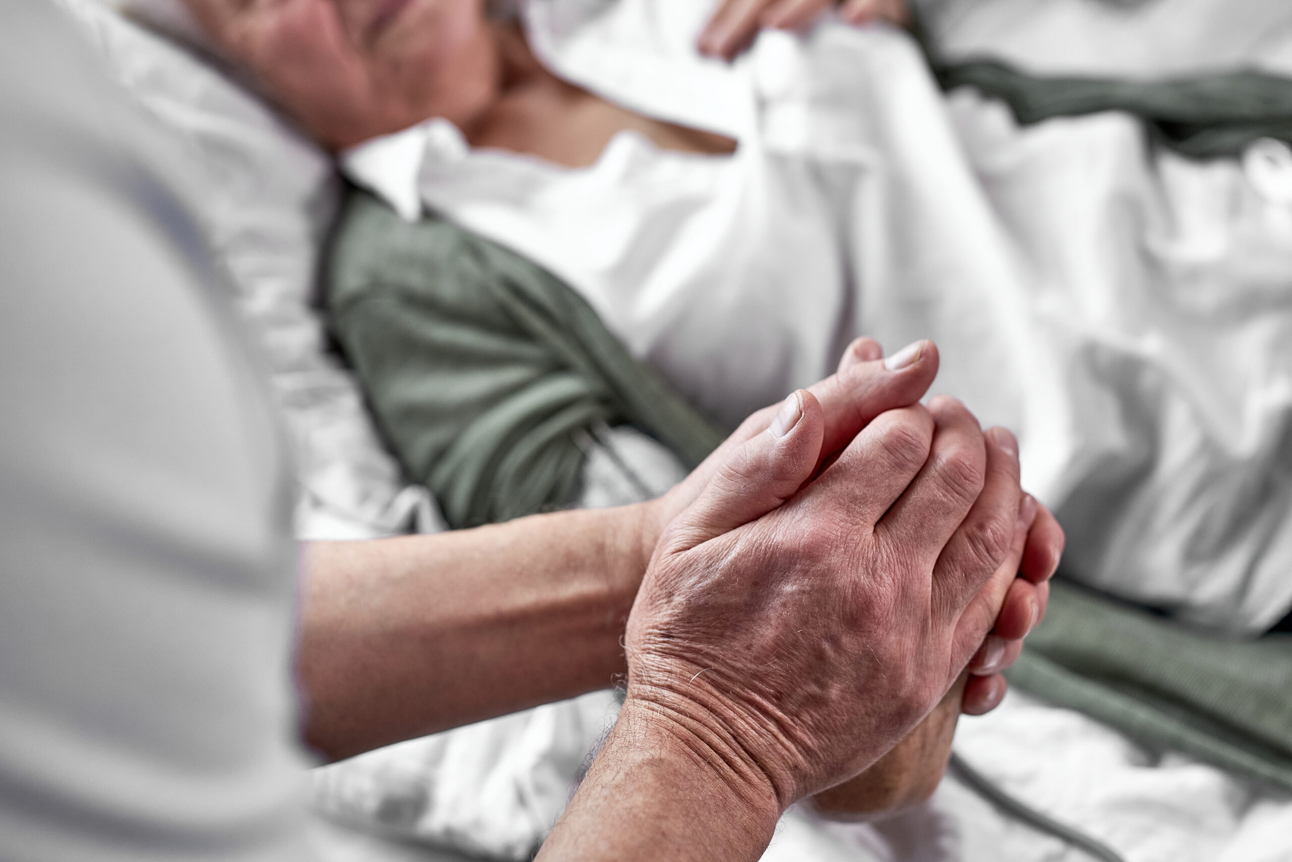 elderly man crying and mourning the loss of his wife, sitting by her side